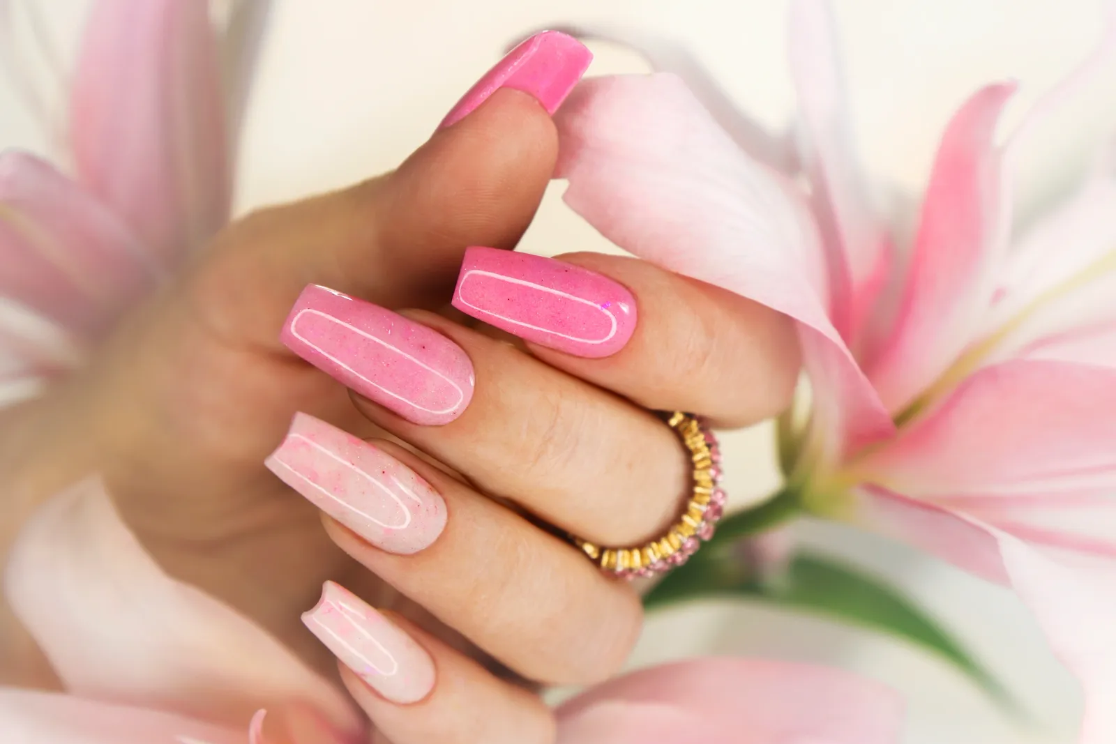 Pink glitter gel nail extensions beside flowers